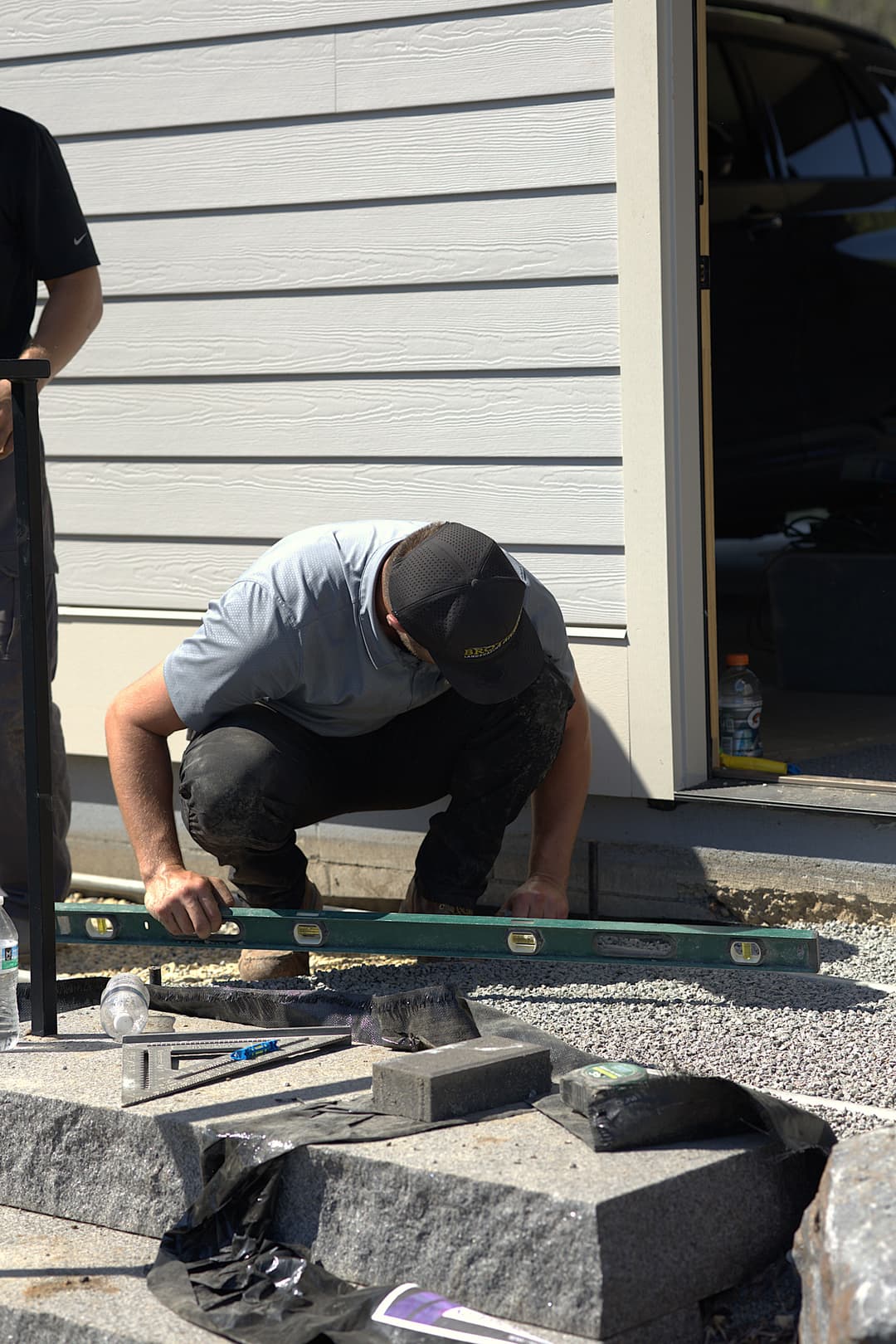 Man using a level tool for precise measurement while laying stones outdoors.