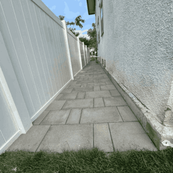 A white fence lines a sidewalk beside a house, creating a neat boundary and enhancing the home's curb appeal.